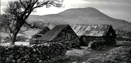 a black and white photo of a stone house in the country